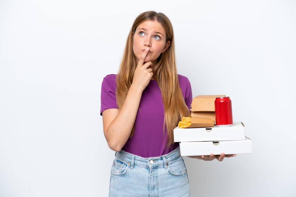 blonde woman holding many fast food items