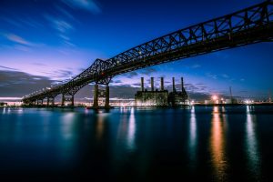 Twilight view of the Pulaski Skyway bridge spanning the Passaic River in Newark, New Jersey, with reflections on the water and industrial buildings below