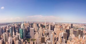 Panoramic aerial view of Midtown Manhattan skyscrapers on a clear day, with Central Park and the East River visible in the background