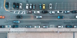 A busy outdoor parking lot with many cars parked closely together near a large building.